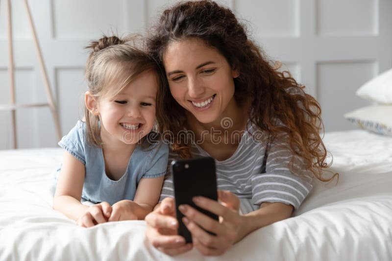 Unga mamma och liten dotter använder smartphone tillsammans royaltyfri bild