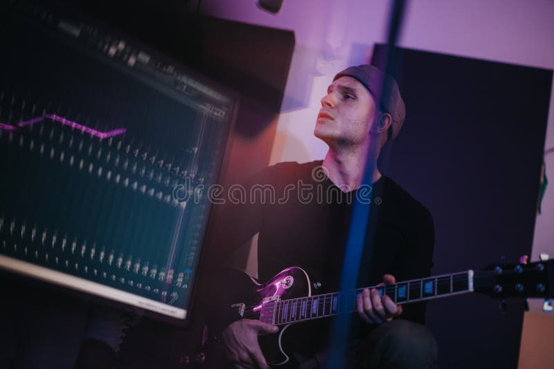 Unga musiker som spelar elgitarr i en kreativ studieläge arkivfoton