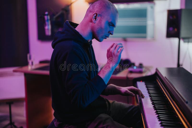 Unga musiker som utövar piano i en futuristisk inspelningsstudio royaltyfri foto