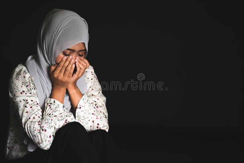 Unga muslimska flickor som sitter i mörka rum och känner smärta i livshotande tillstånd Kläder av muslimska kvinnor som håller sm