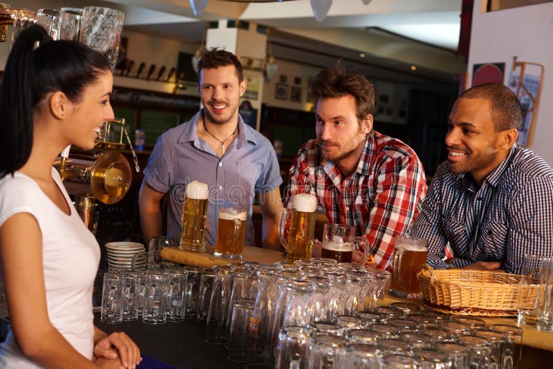 Unga män som flörtar med bartendern i bar arkivbilder Unga män som flörtar med bartendern i bar arkivbilder