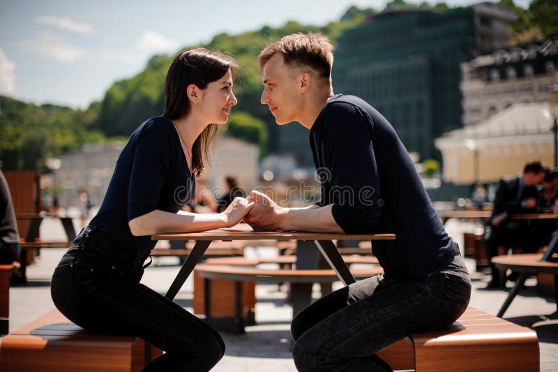 Unga och attraktiva parinnehavhänder omkring som ska kyssas över tabellen i restaurang royaltyfri fotografi Unga och attraktiva parinnehavhänder omkring som ska kyssas över tabellen i restaurang royaltyfri fotografi