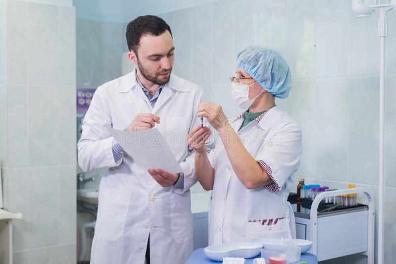 Unga och höga kemister som tillsammans arbetar och ser en provrör i ett kliniskt laboratorium arkivfoto Unga och höga kemister som tillsammans arbetar och ser en provrör i ett kliniskt laboratorium arkivfoto