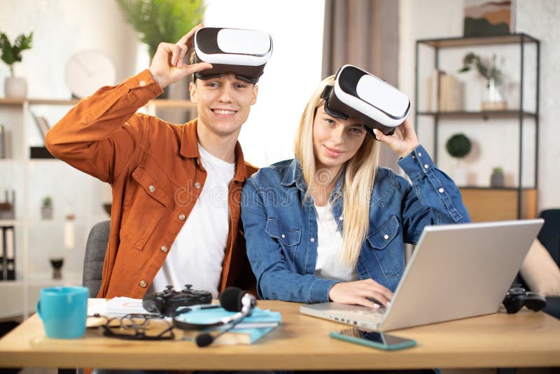 Unga par som använder vr headset och bärbar dator för att spela spel royaltyfri foto