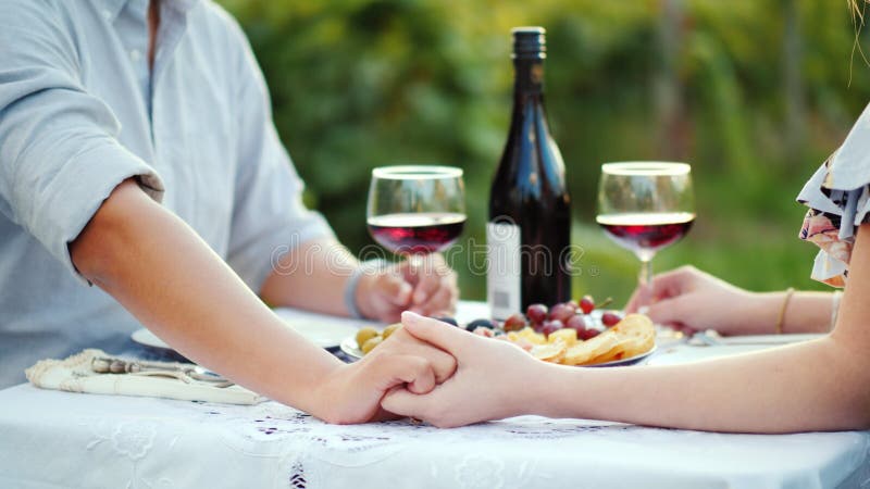 Unga par som rymmer händer, romantisk matställe med vin arkivfoton Unga par som rymmer händer, romantisk matställe med vin arkivfoton