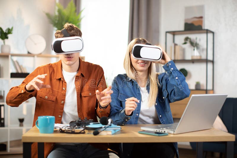 Unga vänner som sitter vid bordet med vr headset och njuter av 3d-verkligheten royaltyfria foton