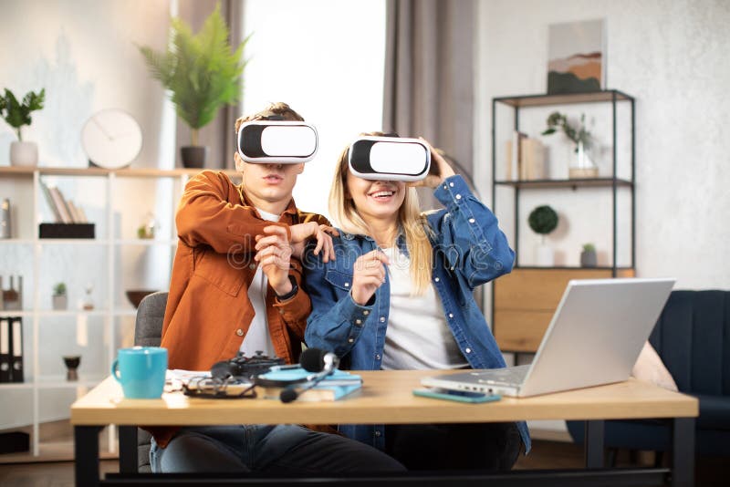 Unga vänner som sitter vid bordet med vr headset och njuter av 3d-verkligheten arkivbilder