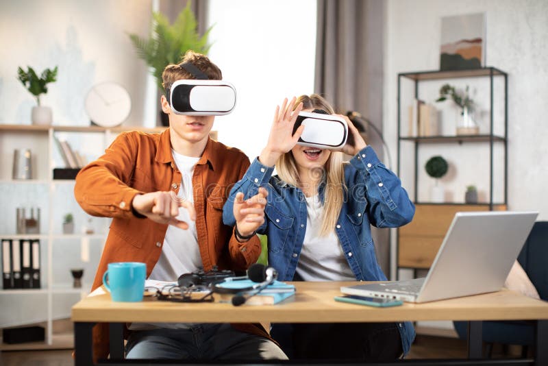 Unga vänner som sitter vid bordet med vr headset och njuter av 3d-verkligheten arkivfoton