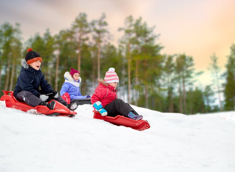 Ungar som glider på slädar snöar ner, kullen i vinter arkivbilder Ungar som glider på slädar snöar ner, kullen i vinter arkivbilder