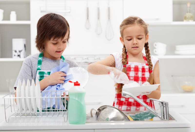 Kids washing the dishes in the kitchen together - helping out with the home chores. Kids washing the dishes in the kitchen together - helping out with the home chores