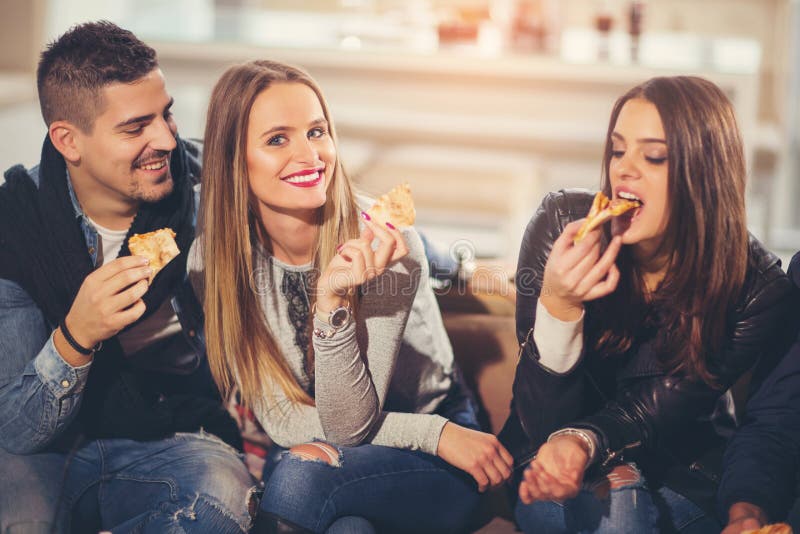 Ungdomari tillfällig kläder som äter pizza royaltyfri bild Ungdomari tillfällig kläder som äter pizza royaltyfri bild