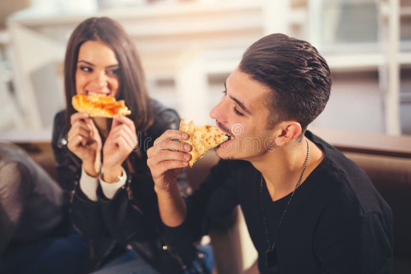 Ungdomari tillfällig kläder som äter pizza royaltyfria foton Ungdomari tillfällig kläder som äter pizza royaltyfria foton