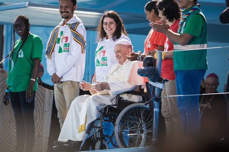 A smiling Pope Francis, surrounded by young people, greets those gathered at the papal altar in Edward VII Park during the welcome to World Youth Day 2023 in Lisbon. A smiling Pope Francis, surrounded by young people, greets those gathered at the papal altar in Edward VII Park during the welcome to World Youth Day 2023 in Lisbon.