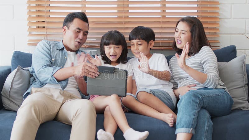 Ungdomsfull asiatisk familjeråda till digitala surfplattor online-videosamtal med vän eller släktingsläkt kusin. Internetteknik
