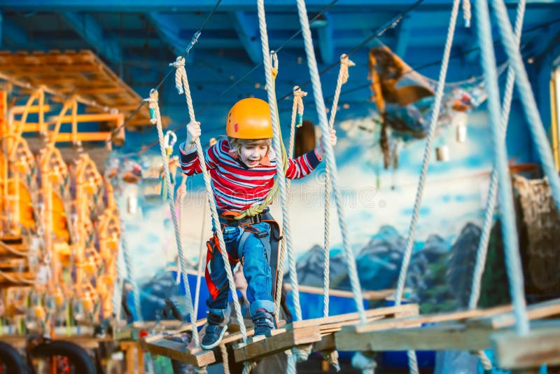 Kid enjoying a summer day and playing. Happy child having fun in adventure park, climbing ropes and laughing. Kid enjoying a summer day and playing. Happy child having fun in adventure park, climbing ropes and laughing.