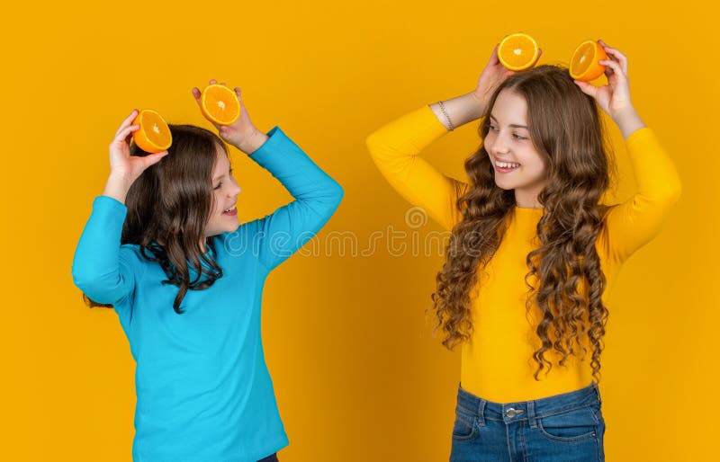 Ungefär ett barn håller orange frukt mot gul bakgrund