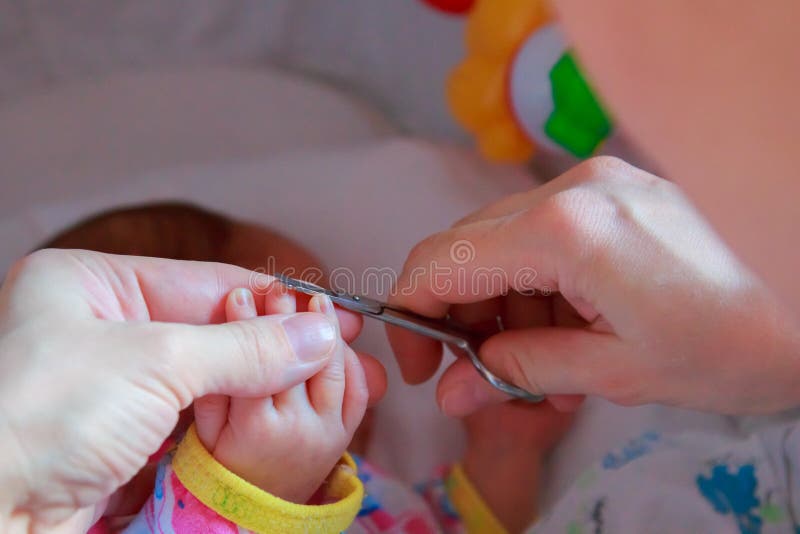 Unghie di taglio ad un neonato che una piccola madre si preoccupa immagini stock libere da diritti Unghie di taglio ad un neonato che una piccola madre si preoccupa immagini stock libere da diritti