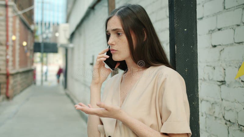 Unglücklich und wütend junge Frau diskutieren Problem auf Handy im Freien stehen