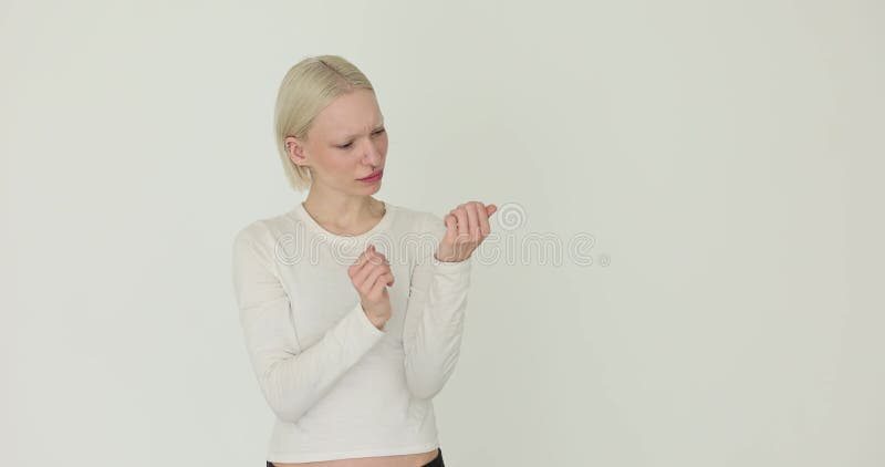 Unglückliche Frau, die ihre Nägel anschaut und mit Maniküre auf weißem Hintergrund unzufrieden ist stock footage