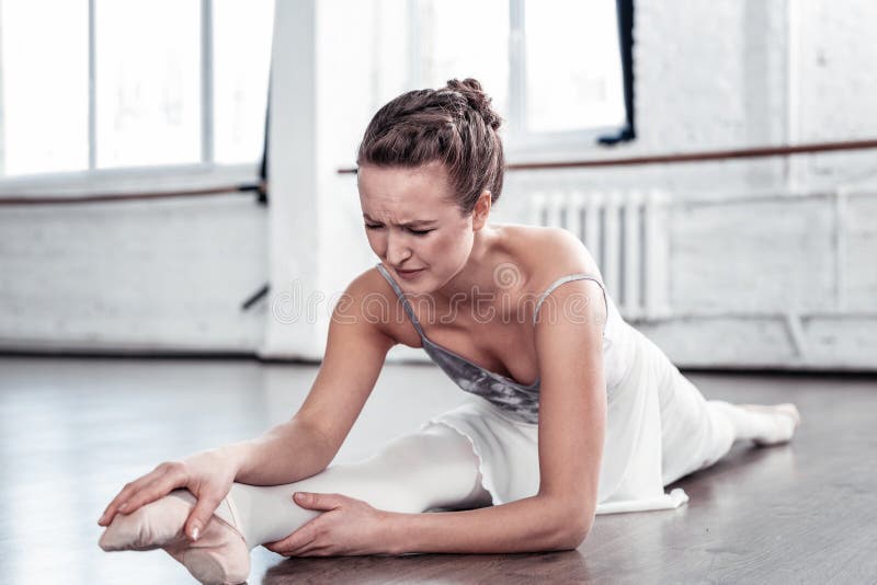 Staying persistent. Unhappy persistent woman continuing doing the exercise while feeling strong pain. Staying persistent. Unhappy persistent woman continuing doing the exercise while feeling strong pain