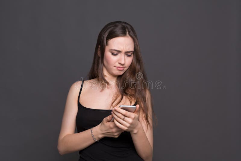 Unglückliche junge Frau, die Smartphoneporträt verwendet stockfotos Unglückliche junge Frau, die Smartphoneporträt verwendet stockfotos