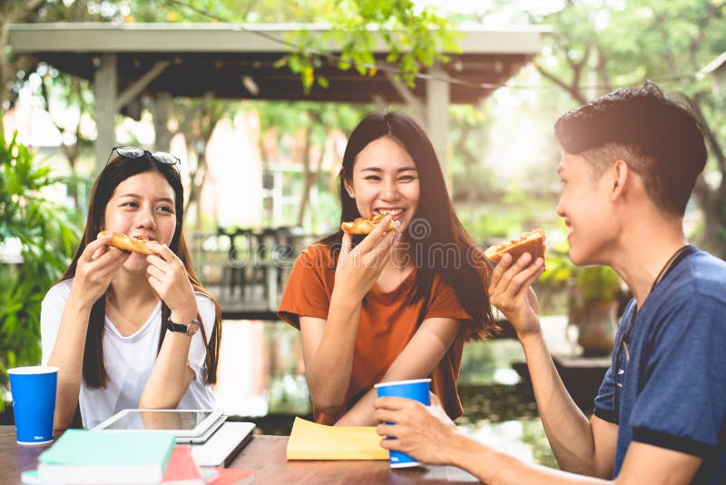 Ungt asiatiskt folk som tillsammans äter pizza vid händer Begrepp för mat- och kamratskapberömparti Livsstilar och folk i tema
