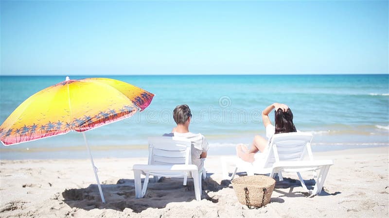 Ungt par på vit strand under sommarsemestern.