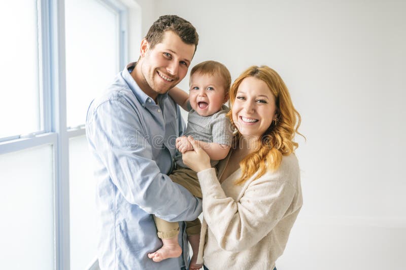 Ungt, vackert familjepar med babypojke på grå studio royaltyfri bild