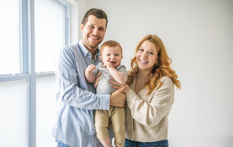 Ungt, vackert familjepar med babypojke på grå studio royaltyfria bilder