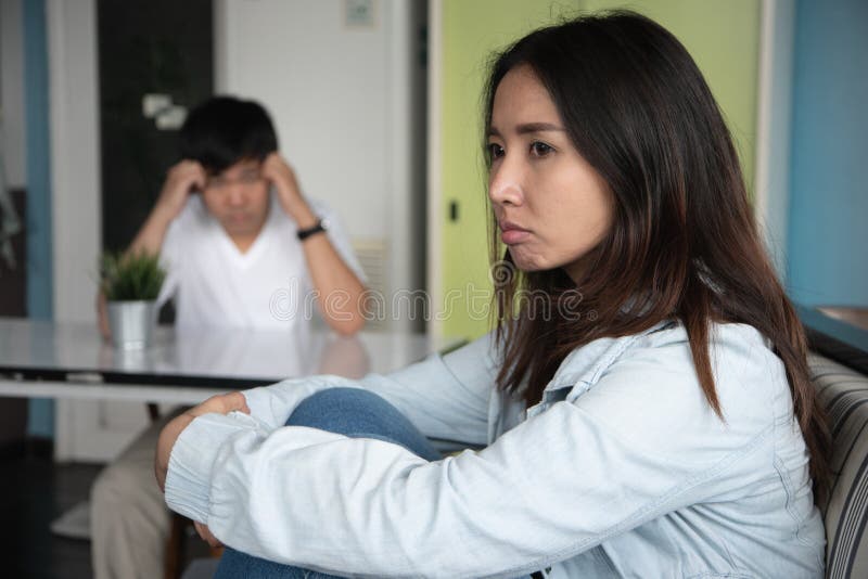 Unhappy couple not talking after an argument at home. depressed woman sitting on the sofa and sad man sitting on the table.