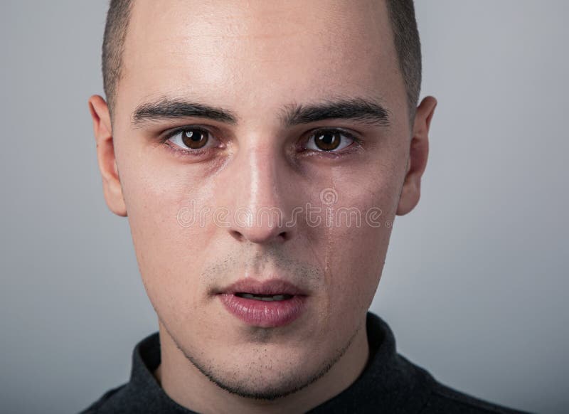 Unhappy crying young man with dropping tears on the face. Closeup studio portrait on grey background. royalty free stock photos Unhappy crying young man with dropping tears on the face. Closeup studio portrait on grey background. royalty free stock photos