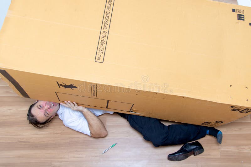 The unhappy man lying under a big box. royalty free stock photos The unhappy man lying under a big box. royalty free stock photos