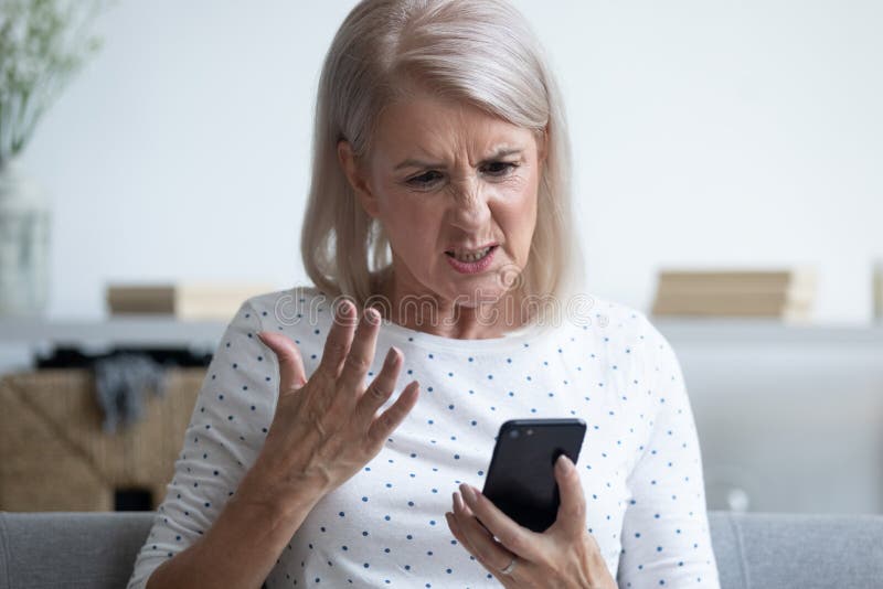 Unhappy middle aged lady irritated by bad smartphone work. stock photography Unhappy middle aged lady irritated by bad smartphone work. stock photography