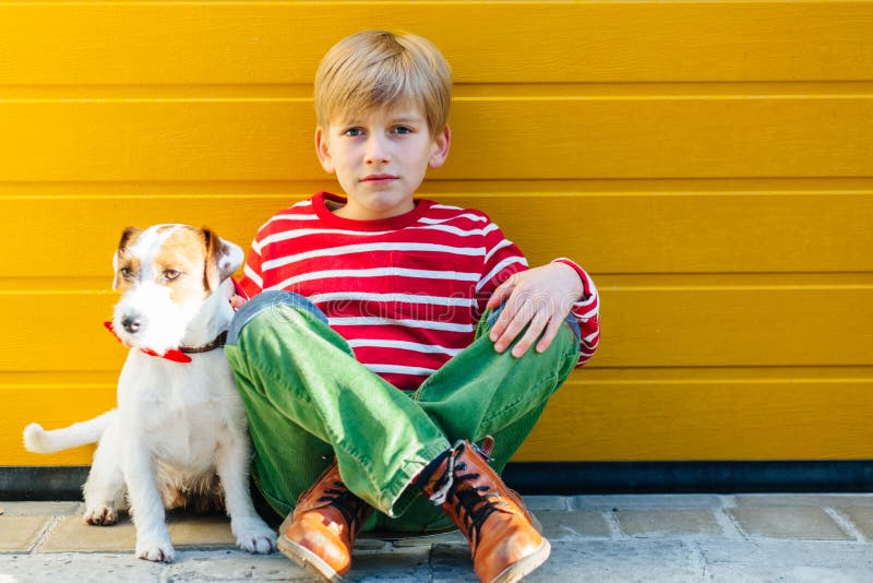 Unhappy sad preteen boy sitiing on the ground with his dog Jack Russell Terrier