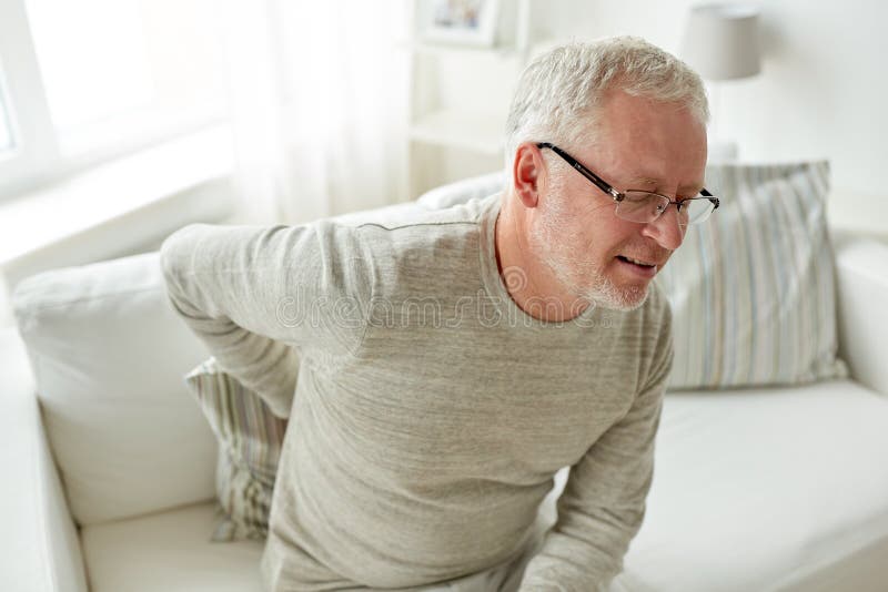Unhappy senior man suffering from backache at home