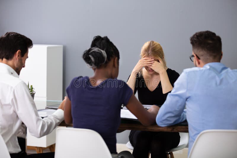 Unhappy Woman Sitting In Front Of Managers In Office royalty free stock photos