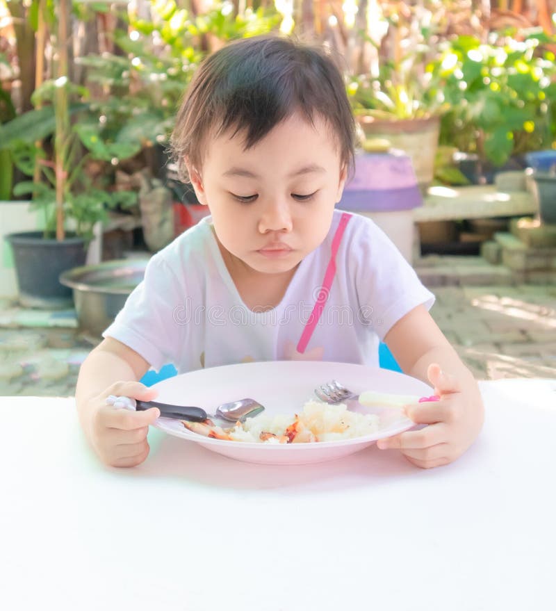 Asian little girl eating tasteless food for lunch, loss of appetite