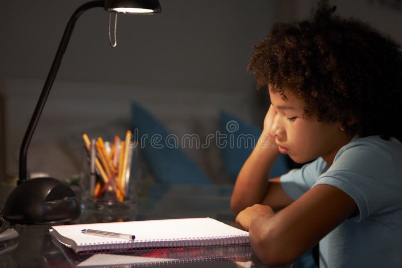 Unhappy Young Boy Studying At Desk In Bedroom In Evening stock photography Unhappy Young Boy Studying At Desk In Bedroom In Evening stock photography