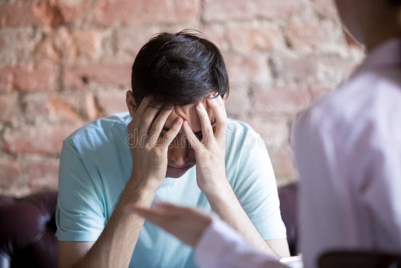Unhappy young man at a psychologist counselor reception. royalty free stock photography