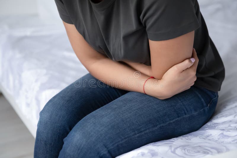 Unhealthy young woman suffer from abdominal pain at home. Close up of young woman sit on bed suffer from abdominal pain having intoxication or poisoning royalty free stock photos Unhealthy young woman suffer from abdominal pain at home. Close up of young woman sit on bed suffer from abdominal pain having intoxication or poisoning royalty free stock photos