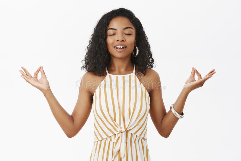 Unidade do sentimento com o universo durante todo a meditação Modelo fêmea de pele escura encantador calmo calmo no amarelo listr foto de stock Unidade do sentimento com o universo durante todo a meditação Modelo fêmea de pele escura encantador calmo calmo no amarelo listr foto de stock
