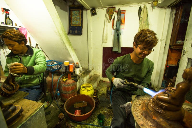 Unidentified Nepalese tinman working in the his workshop. stock image