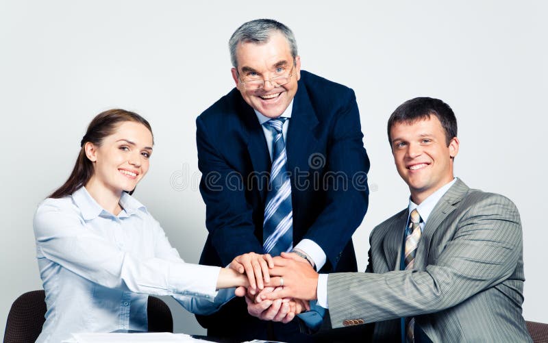 Photo of three partners putting their hands on the top. Photo of three partners putting their hands on the top