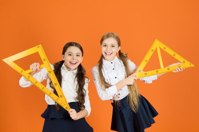 Uniforme escolar de los niños en fondo anaranjado Muchachas lindas del alumno con las reglas grandes Tema de escuela de la geomet fotografía de archivo Uniforme escolar de los niños en fondo anaranjado Muchachas lindas del alumno con las reglas grandes Tema de escuela de la geomet fotografía de archivo