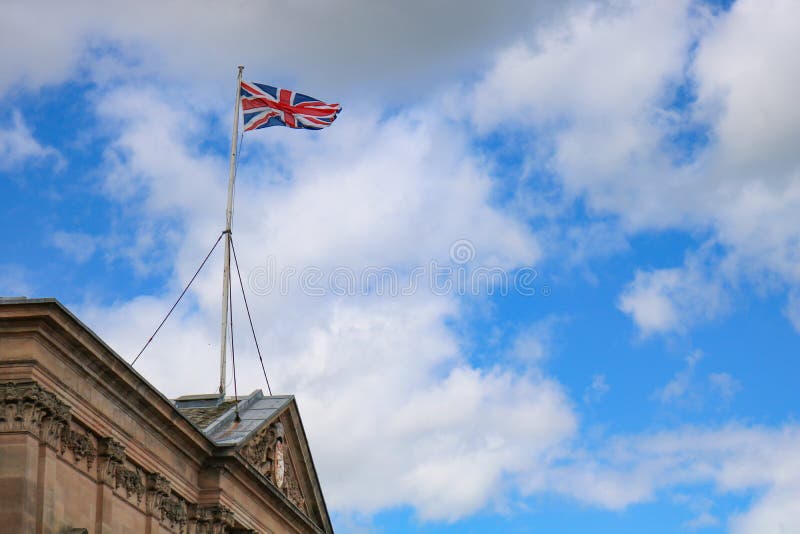 Union jack flag flying above old british building in united kingdom. With blue sky stock photos