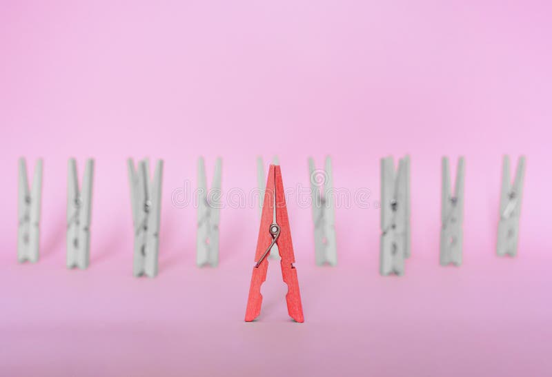 Unique, individuality, outstanding,leadership and think different concept. Red wooden clip stand out of colorless clips on blue ba stock image Unique, individuality, outstanding,leadership and think different concept. Red wooden clip stand out of colorless clips on blue ba stock image