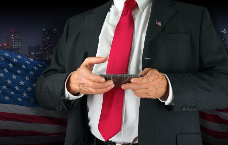 United States of America politician texting on his cell phone. Closeup of a United States of America politician with red neck tie and American flag lapel pin royalty free stock photography United States of America politician texting on his cell phone. Closeup of a United States of America politician with red neck tie and American flag lapel pin royalty free stock photography
