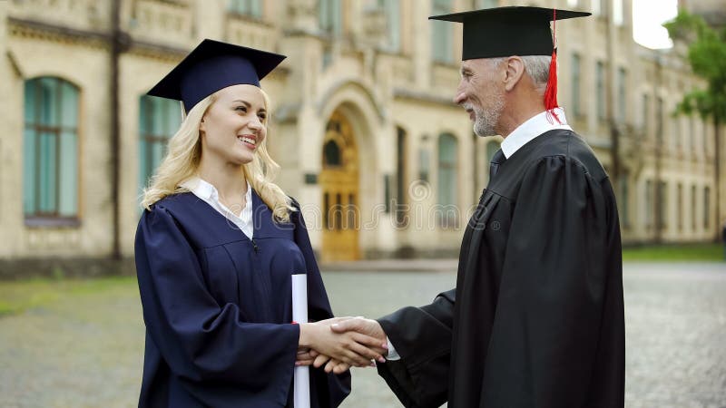 Universitetkansler som ger diplomet till studenten, gratulerar och skakar handen royaltyfria bilder Universitetkansler som ger diplomet till studenten, gratulerar och skakar handen royaltyfria bilder