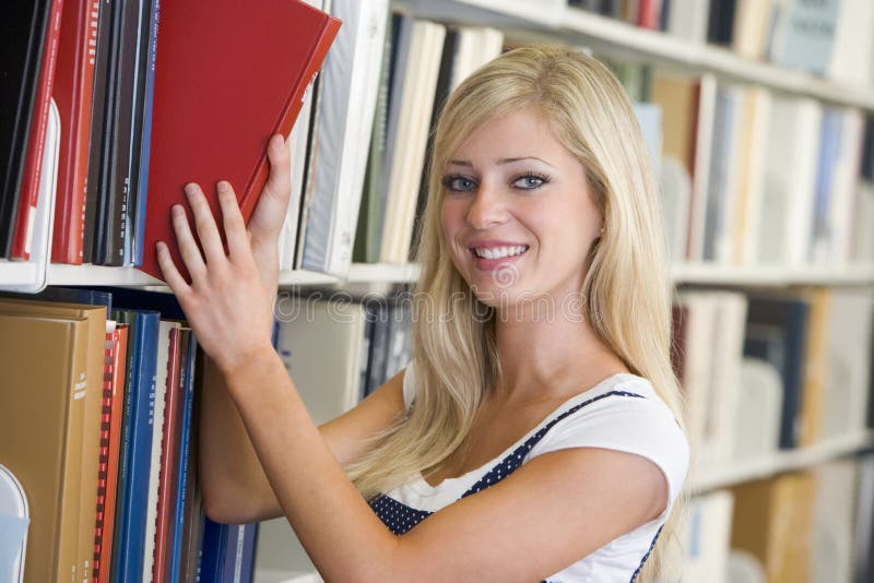 University student selecting book from library stock photos