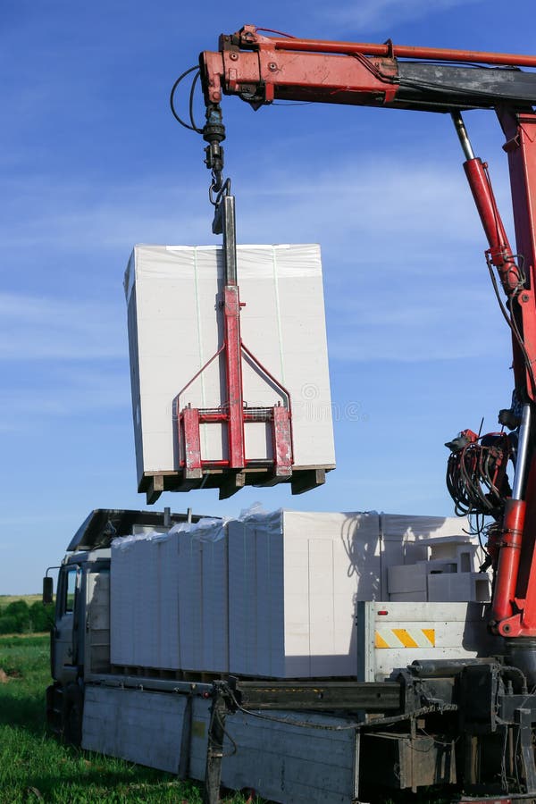 Unloading Building Blocks from a Truck Using a Crane. Hydraulic